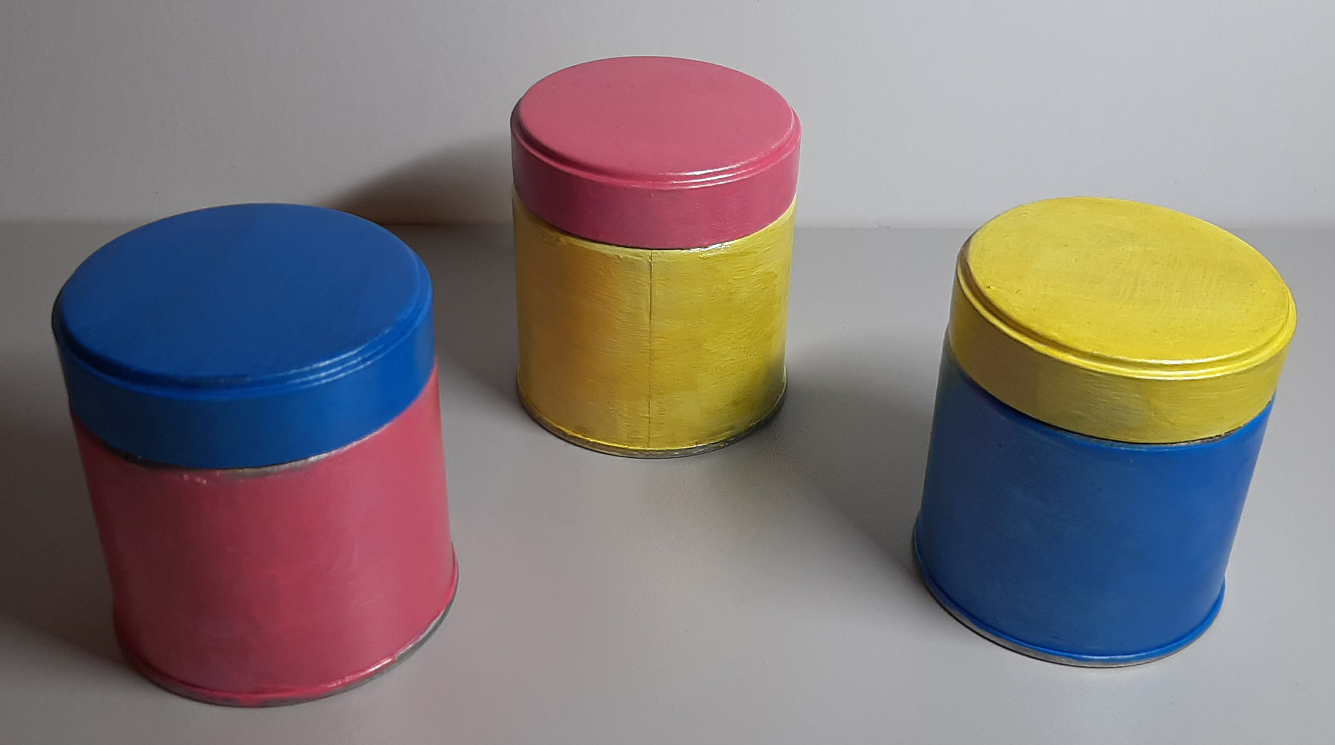 3 cans painted blue, pink, and yellow